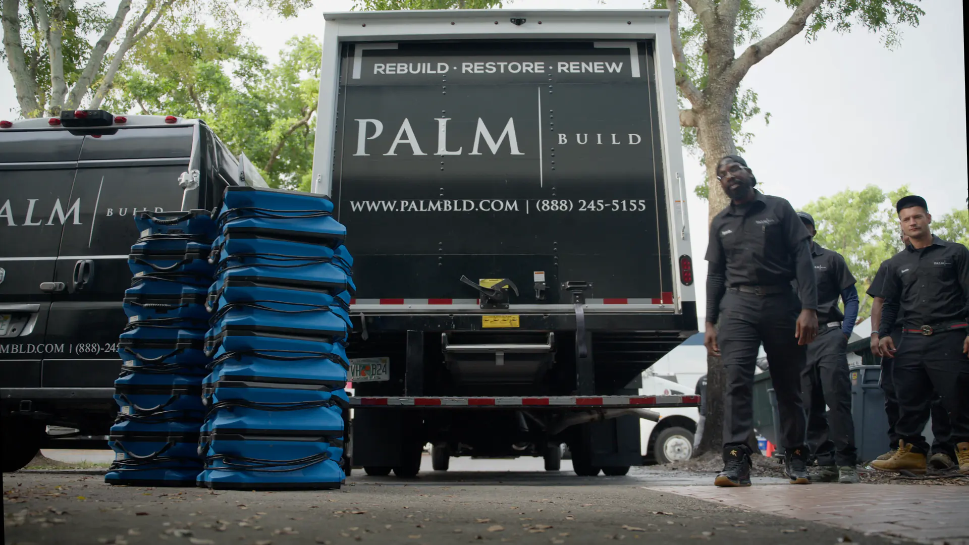 Palm Build restoration crew lined up behind a branded Palm Build box truck with stacked air movers, ready to respond